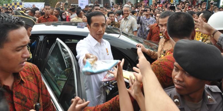 Presiden Jokowi membagikan kaos dan buku usai keluar dari lokasi groundbreaking Rusunawa, Kelurahan Gedanganak, Ungaran Barat, Kabupaten Semarang, Rabu (29/4/2015) siang. 