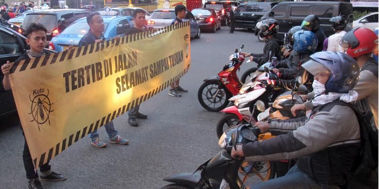 Para anggota komunitas membentangkan spandung imbauan pada pengendara sepeda motor.