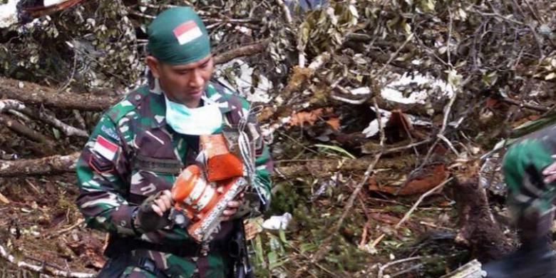 Foto yang dirilis oleh Kodam XVII/ Cendrawasih, 18 Agustus 2015, memperlihatkan seorang tentara menyelamatkan kotak hitam atau flight data recorder di antara puing pecahan pesawat Trigana Air ATR 42-300 yang jatuh di kawasan pegunungan di Oksibil, Papua.
