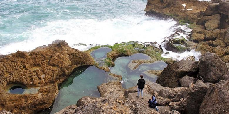 Dua  wisatawan tengah menikmati panorama Pantai Kedung Tumpang di Pucanglaban, Kabupaten Tulungagung, Jawa Timur, Jumat (14/8/2015) sore. Kondisi pantai yang alami, deburan ombak, dan kolam-kolam alami di atas hamparan karang menjadi pesona yang menakjubkan  wisatawan meski infrastruktur masih minim.