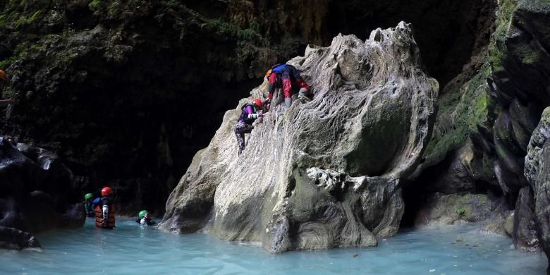 Beberapa peserta cave tubing berusaha memanjat salah satu batu yang terdapat di bagian Goa Kalisuci, Gunungkidul, DI Yogyakarta untuk berpose di goa yang eksotis tersebut.