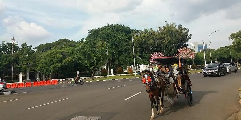 Sejumlah pengunjung memanfaatkan musim libur akhir tahun 2015 dengan menaikki delman sambil berkeliling Monumen Nasional (Monas), Jakarta Pusat pada Kamis (24/12/2015)