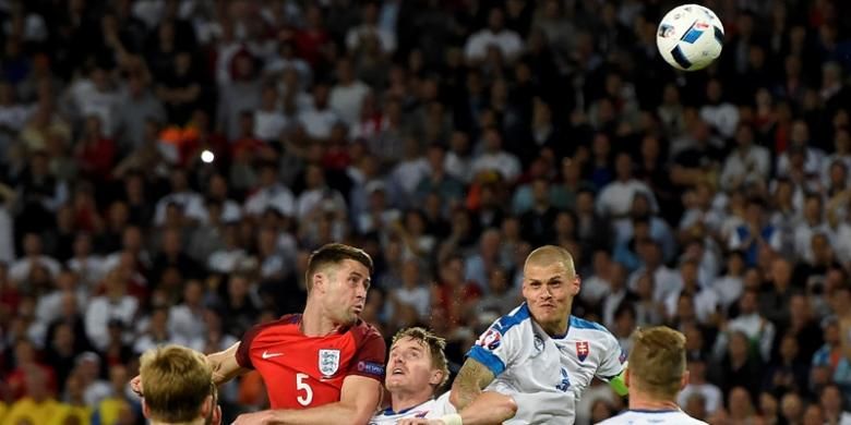 Bek Inggris, Gary Cahill, menyundul bola dalam kawalan ketat bek Slovakia, Tomas Hubocan (tengah), dan Martin Skrtel (tengah kanan) pada pertandingan Grup B Piala Eropa 2016 di Stadion Geoffroy-Guichard, Saint-Etienne, Senin (20/6/2016). 