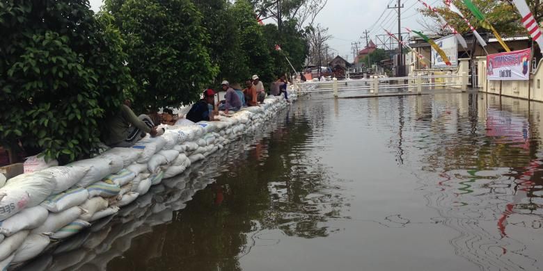 Ilustrasi air rob di menggenangi Kali Sringin dibendung menggunakan tanggul sementara di depan Mapolsek Genuk, Semarang.