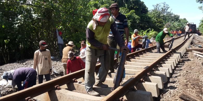 Sejumlah petugas saat memperbaiki rel kereta yang jebol karena diterjang banjir di Dusun Botokan, Desa Tambakrejo, Kecamatan Kraton, Kabupaten Pasuruan, Jumat (1/7/2016)