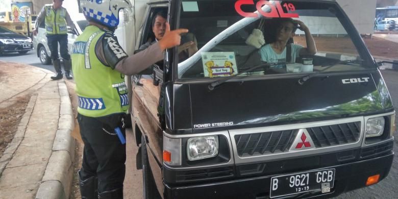 Petugas kepolisian sedang memberikan sanksi tilang kepada pengemudi kendaraan berpelat nomor ganjil di kolong flyover Kuningan pada Selasa (30/8/2016).