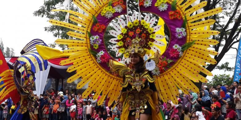 Salah satu peserta Malang Flower Carnival (MFC) memperagakan kostum yang dikenakannya, Minggu (4/9/2016), di Kota Malang, Jawa Timur.