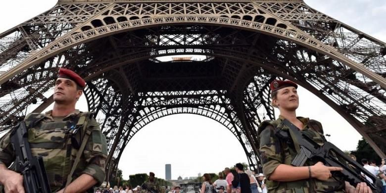 Tentara berjaga di kaki Menara Eiffel, Paris, Perancis. Menara ini berada di sebuah taman yang luas, yang disebut Champs de Mars. 