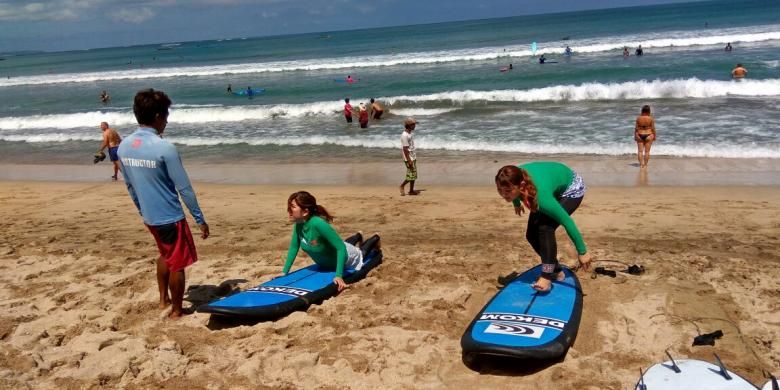 Turis Jepang sedang belajar surfing di Pantai Kuta, Bali.