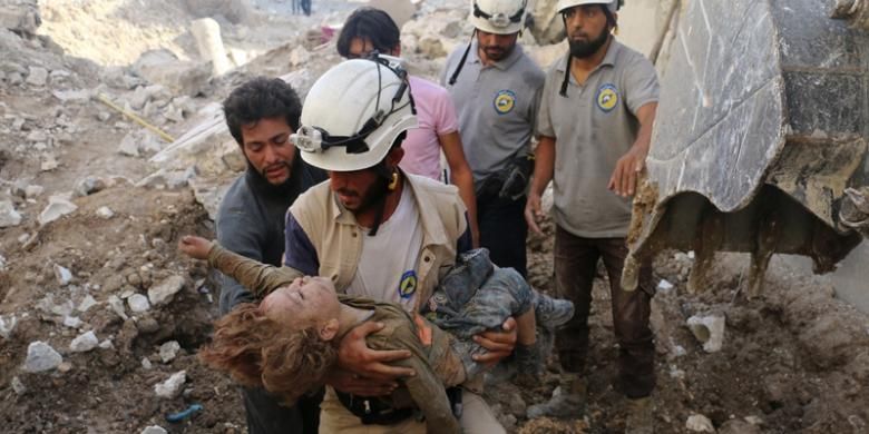 Seorang anggota kelompok sukarelawan White Helmets alias Helm Putih membopong jasad seorang anak perempuan dari reruntuhan rumahnya yang hancur dihantam bom di Aleppo, Suriah.