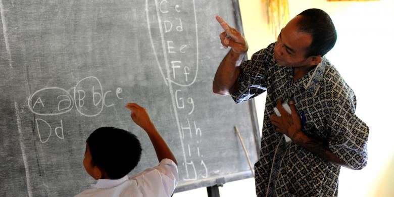 Guru mengajar menggunakan bahasa isyarat kepada seorang murid tunarungu di Sekolah Dasar, di Desa Bengkala, Singaraja, Bali, 20 Juli 2016. Desa Bengkala telah menjadi rumah bagi sejumlah besar penyandang tunarungu turun temurun.