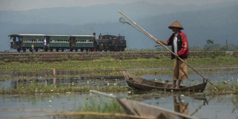 Lokomotif uap B 5112 yang melintasi Danau Rawa Pening di Kecamatan Bawen, Kabupaten Semarang, Jawa Tengah, menarik gerbong kereta wisata dari Stasiun Ambarawa menuju Stasiun Tuntang, Sabtu (24/9/2016). Lokomotif buatan pabrik Hannoversche Maschinenbau AG di Jerman tahun 1902 itu menjadi salah satu daya tarik wisata utama Museum Kereta Api Ambarawa. 