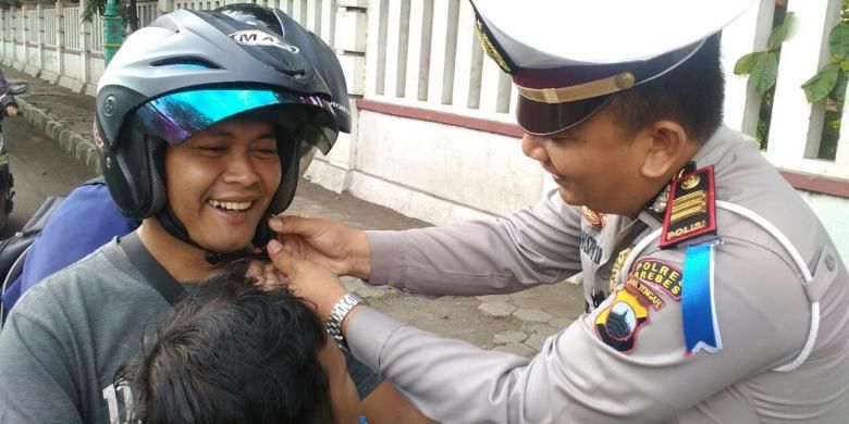 Kasatlantas Polres Brebes AKP Arfan Zulkan Sipayung memasang helm ke pengendara motor saat Ops Zebra 2016 di Jalan Jenderal Sudirman, Brebes, Jawa Tengah.