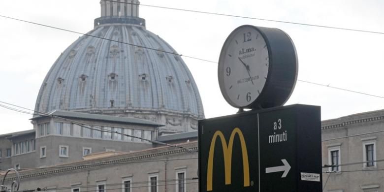 Lambang restoran cepat saji McDonalds dengan latar belakang kubah Basilika Santo Petrus, Vatikan.