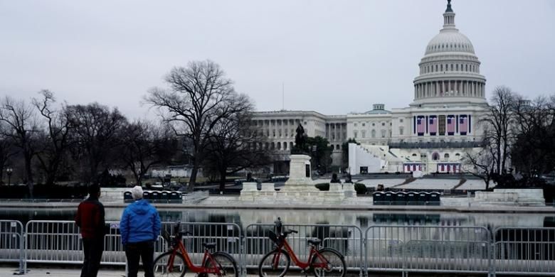 Sejumlah turis menyaksikan Gedung Capitol yang tengah disiapkan untuk prosesi pelantikan presiden baru AS, Jumat (20/1/2017).