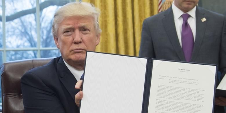 Presiden AS Donald Trump memperlihatkan perintah eksekutif yang mengeluarkan AS dari kerjasama trans-pasifik (TPP). Keputusan ini ditandatangani Trump di Ruang Oval, Senin (23/1/2017).