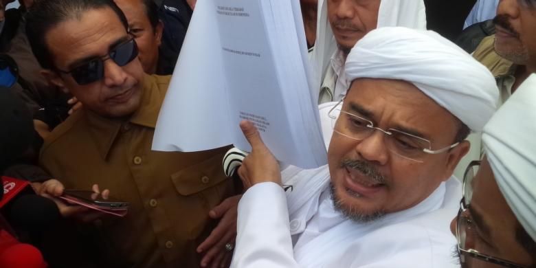 Pemimpin Front Pembela Islam Rizieq Shihab menunjukkan tesisnya sebelum diperiksa oleh penyidik Polda Jawa Barat, Senin (13//2/2017). 