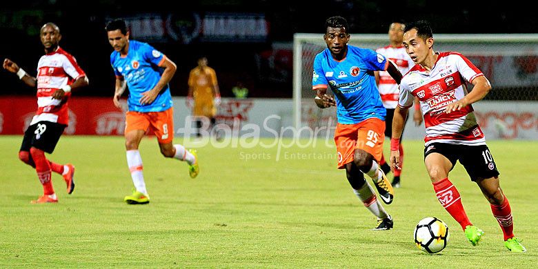 Gelandang Madura United, Slamet Nurcahyono, berupaya melewati hadangan pemain belakang Perseru Serui, Kelvin Wopi, dalam laga pekan ke-16 Liga 1 2018 di Stadion Ratu Pamellingan Pamekasan, Jawa Timur, Selasa (16/07/2018) malam.
