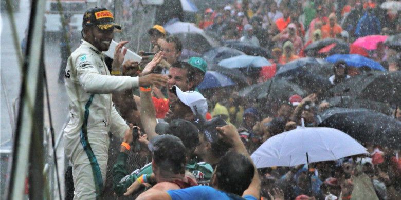 Pebalap Mercedes, Lewis Hamilton, menyapa penggemarnya setelah memenangi balapan GP Jerman di Sirkuit Hockenheim, Jerman, Minggu (22/7/2018).
