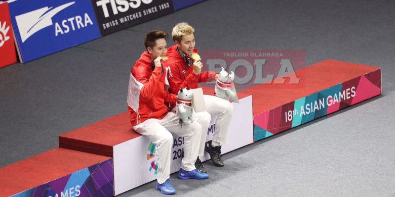 Marcus Fernaldi Gideon (kanan) dan Kevin Sanjaya Sukamuljo (kiri) memegang medali emas usai menjuarai cabang bulu tangkis nomor ganda putra Asian Games 2018, Selasa (28/8/2018).
