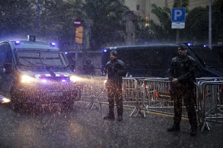 Petugas kepolisian lokal Catalonia, atau biasa disebut Mosso dEsquadra,  berdiri menjaga demonstran warga Catalonia pro-kemerdekaan di depan delegasi pemerintah Spanyol di Barcelona, 19 Oktober 2017. 