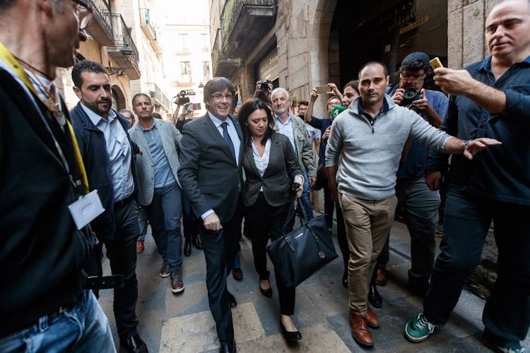 Pemimpin Catalonia Carles Puigdemont (tengah-kiri), yang secara resmi telah dicopot oleh otoritas di Madrid, berjalan didampingi istrinya, Marcela Topor (tengah-kanan) di Girona pada Sabtu (28/10/2017). 