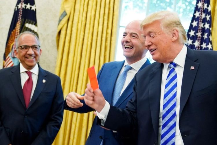 Presiden FIFA Gianni Infantino (tengah) tertawa saat Presiden AS Donald Trump memegang kartu merah selama pertemuan di Oval Office Gedung Putih pada Selasa (28/8/2018).  (AFP/Mandel Ngan)