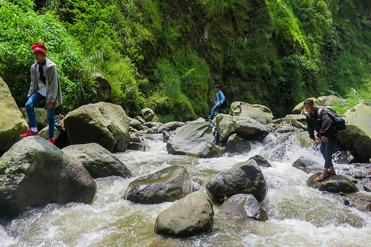 Menyeberangi sungai menuju Air Terjun Kedung Kayang salah satunya bisa dilakukan dengan melompat di antara bebatuan. Berani?