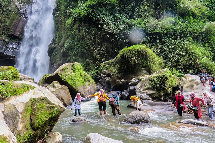 Pengunjung menyeberangi sungai menuju Air Terjun Kedung Kayang.