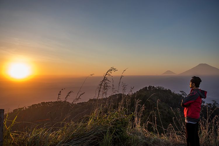 Seorang pengunjung menikmati momen sunset yang tersaji di Puncak Gunung Kunir Purworejo.