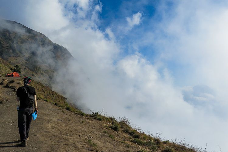 Seorang pendaki Gunung Rinjani berjalan di samping awan di Plawangan Sembalun.