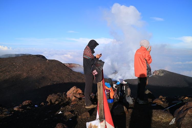 Pendaki di puncak Gunung Slamet, Jawa Tengah dengan latar belakang kawah gunung api. Gunung Slamet merupakan salah satu gunung api aktif di Indonesia.