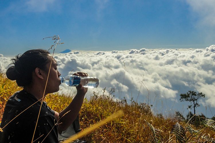 Seorang Pendaki sedang minum di Gunung Sumbing.