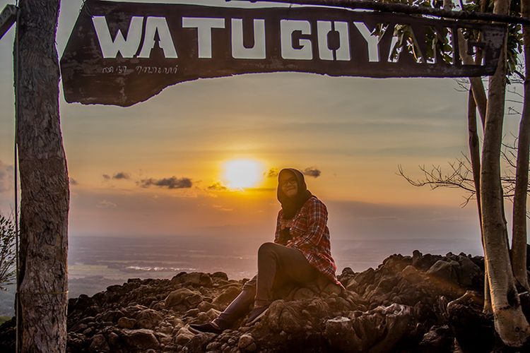 Seorang pengunjung berfoto dengan latar belakang matahari terbanam di Watu Goyang, Bantul, Yogyakarta.