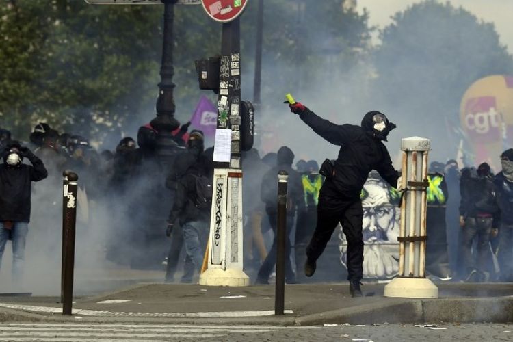 Seorang pengunjuk rasa melempar ke arah petugas polisi pada aksi demonstrasi Hari Buruh Internasional di Paris, Perancis, Selas a(1/5/2018). (AFP/Alain Jordan)