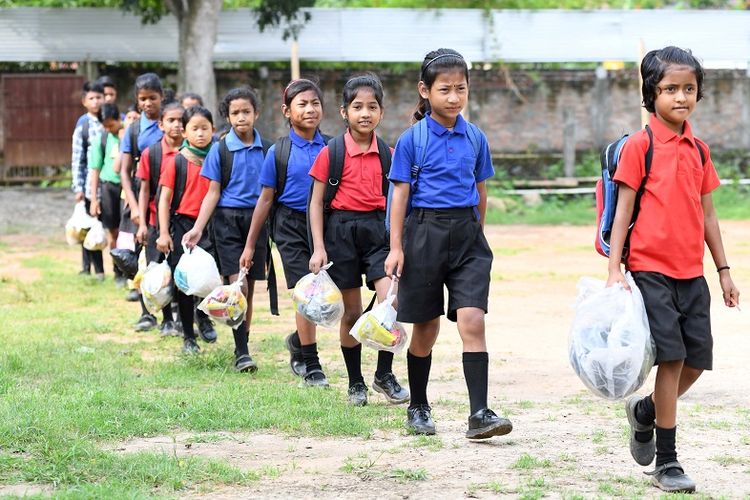 Murid-murid di India mengantre membawa tas plastik berisi sampah plastik untuk diserahkan sebagai pengganti biaya sekolah di sekolah Forum Akshar, Dispur, negara bagian Assam. (AFP/BIJU BORO)