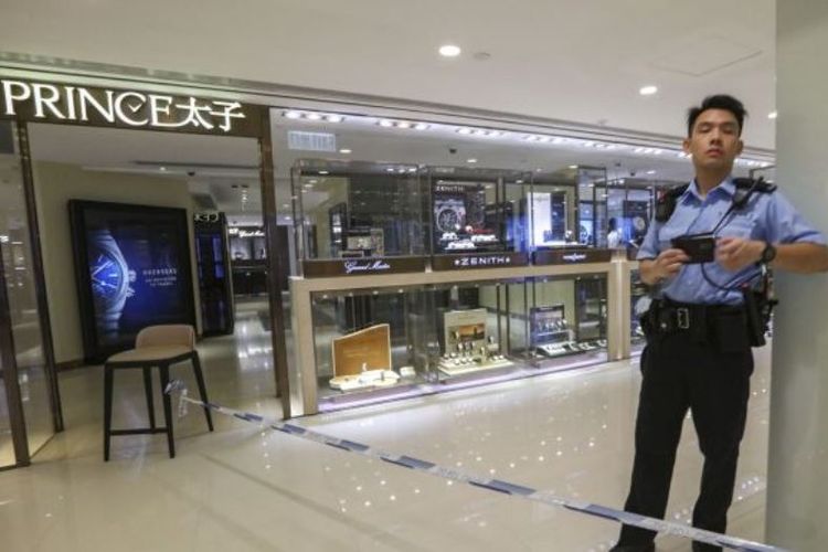 Petugas kepolisian berjaga di depan toko perhiasan yang menjadi sasaran perampokan oelh dua orang di Hong Kong, Rabu (23/5/2018).