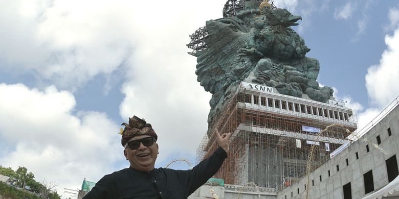 Pemrakarsa Patung Garuda Wisnu Kencana (GWK) Nyoman Nuarta berfoto dengan latar belakang pemasangan bagian Mahkota Dewa Wisnu di Ungasan, Badung, Bali, Minggu (20/5/2018). Mahkota Dewa Wisnu tersebut merupakan modul ke-529 dari total 754 modul yang terpasang di patung setinggi 121 meter yang ditargetkan selesai dibangun pada Agustus 2018.