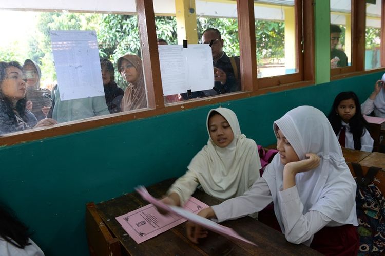 Sejumlah orang tua murid kelas satu (kiri) membantu anaknya mencari kelas pada hari pertama masuk sekolah di SMPN 128 HalimPK, Jakarta, Jumat (13/7). Kegiatan belajar mengajar kembali normal pada Senin (16/7) setelah libur panjang. 