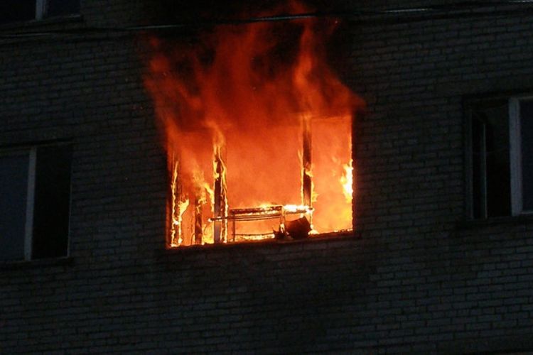 Api terlihat dari jendela bangunan apartemen yang terbakar di Massachusetts, Minggu (18/3/2018), menewaskan setidaknya tiga orang.