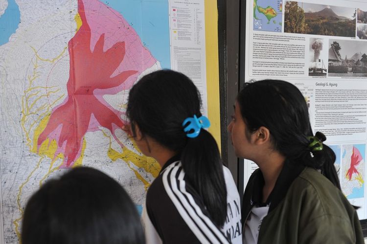 Warga mengamati peta bencana saat turut memantau aktifitas Gunung Agung di Pos Pemantauan Desa Rendang, Karangasem, Bali, Selasa (19/9). Sejak Senin (18/9), status Gunung Agung dinaikkan dari level waspada ke siaga menyusul meningkatnya gempa vulkanik yang terdeteksi melalui pos pemantauan. 