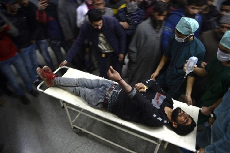 Personel medis membawa seorang pemuda yang terluka akibat tembakan peluru selama bentrokan dengan pihak berwenang, di Srinagar, India, Sabtu (15/12/2018). (AFP/Tauseef Mustafa)