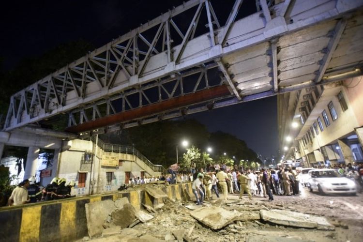 Warga dan pekerja penyelamat berkumpul di lokasi jembatan penyeberangan orang ambruk, di luar kompleks Stasiun Shivaji Maharaj Terminus di Mumbai, India, Kamis (14/3/2019). (AFP)