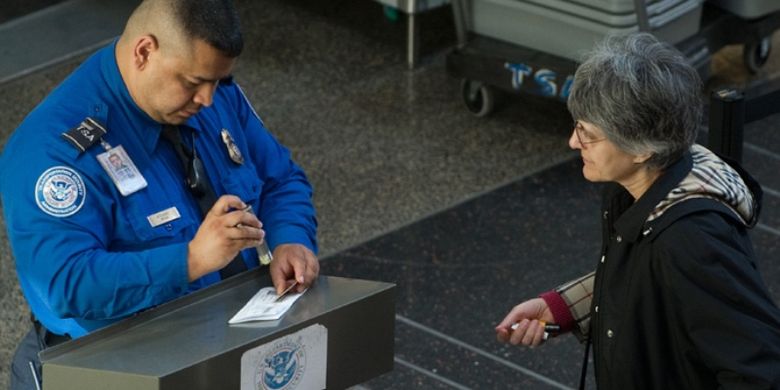 Seorang petugas Badan Keamanan Transportasi (TSA) memeriksa identitas penumpang di boarding pass di bandara nasional Ronald Reagan, Arlington, Virginia.