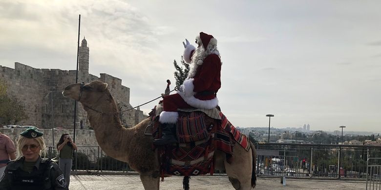 Mantan pemain basket, Issa Kassassieh, mengenakan kostum Sinterklas, dan menaiki unta menebarkan perayaan Natal di jalan-jalan Yerusalem (21/12/2017).