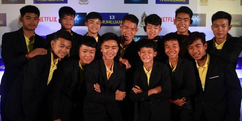 Anggota tim sepak bola Wild Boars berpose untuk berfoto dengan pelatih mereka Ekkapol Chantawong (belakang tengah) selama konferensi pers di Bangkok, Thailand, Selasa (30/4/2019) setelah menandatangani kesepakatan dengan Netflix. (AFP/Lilian Suwanrumpha)