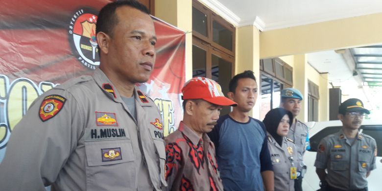 Guru PNS AS (bertopi) sebelum memberikan keterangan pers di Mapolres Garut, Selasa (21/5/2019). AS dotangkap karena menyebarkan pesan pengeboman massal di Jakarta via WhatsApp. 