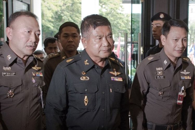 Dalam foto yang diambil pada 3 Juni 2015, terliihat Letjen Manas Kongpan (tengah) diapit sejumlah perwira polisi saat menyerahkan diri di Bangkok. 