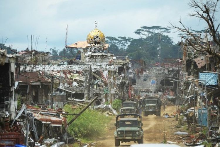 Mobil militer tampak melewati jalanan yang dihiasi dengan reruntuhan bangunan di Marawi, Filipina. (AFP/Ted Aljibe)