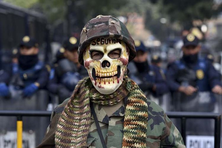 Seorang penggiat HAM mengenakan kostum seperti militer ketika berunjuk rasa di Meksiko. Aksi itu dilakukan setelah pemerintah Meksiko menyepakati peraturan baru yang memberikan kewenangan penuh militer bertindak seperti polisi (14/12/2017).